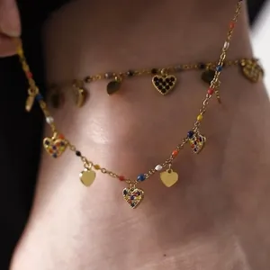 Detailed view of a gold chain anklet featuring colorful crystal heart charms and beads.
