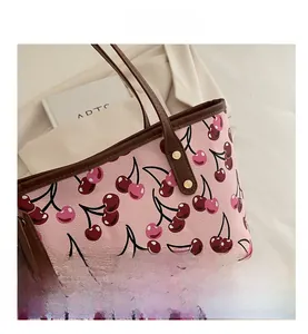 Détail d'un grand sac cabas rose avec imprimé cerises et anses en cuir marron