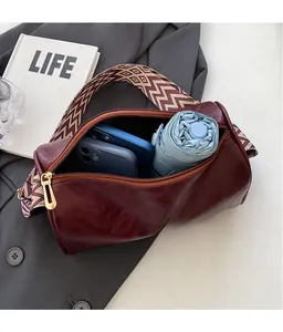 Detailed interior view of a burgundy leather pillow bag with wide geometric strap.