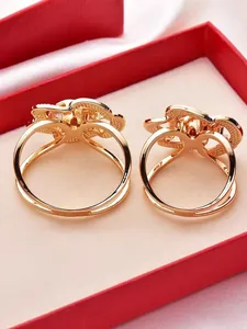 Close-up detail showing the back structure of gold rose-shaped scarf rings in a red box