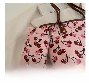 Détail du cabas rose à imprimé cerise avec une petite pochette assortie en accessoire.