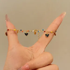 Dainty gold chain anklet featuring colorful enamel beads and black pavé heart charms.