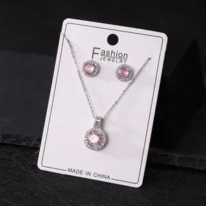 Close-up of elegant pink zircon halo necklace and earrings set on a white display card