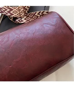 Close-up of textured burgundy faux leather pillow bag with patterned strap
