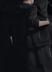 Vista detallada de una chaqueta negra con capucha para hombre en un marco de música creativo.