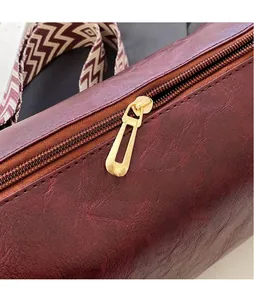 Close-up detail of the smooth gold hardware zipper pull on a brown leather pillow bag