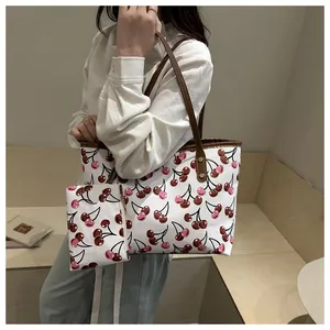 Grand sac cabas à imprimé cerise avec pochette assortie porté par un mannequin.