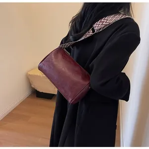 Dark red crossbody pillow bag with a stylish wide patterned strap detail