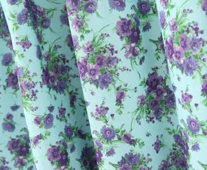 Nahaufnahme von hochwertigem mintblauem Stoff mit elegantem lila Blumendruckmuster