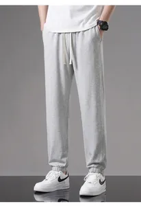 Detailed view of men's light grey cotton joggers featuring a drawstring waist and elastic cuffs