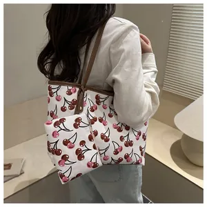 Grand sac fourre-tout blanc avec imprimé cerise porté par un mannequin en tenue décontractée