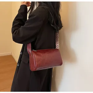 Vintage burgundy cylindrical pillow bag with patterned wide shoulder strap detail