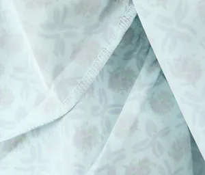 Makroansicht des hellblauen Blumenmusters mit sauberen Overlock-Nähten am Stoff.