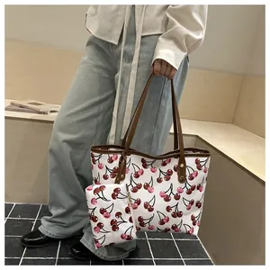 Sac cabas chic à imprimé cerise avec petite pochette assortie tenu par mannequin