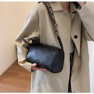 Detail of a black leather pillow bag with a stylish geometric wide shoulder strap.