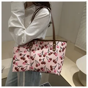 Élégant sac cabas rose à imprimé cerises avec pochette assortie porté par un mannequin