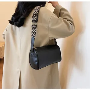 Detailed shot of black cylinder pillow bag featuring a patterned woven wide strap.