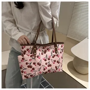 Gros plan du sac cabas rose à imprimé cerise avec sa petite pochette zippée assortie