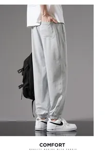Detail of grey men's cotton sweatpants showing loose fit and cuffed ankles