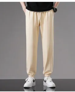 Detailed view of men's beige loose-fit cotton joggers featuring elastic ankle cuffs