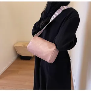 Detail view of pink pillow bag with geometric wide strap on black coat