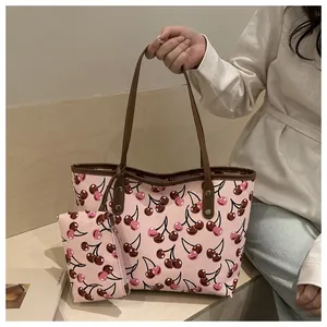 Gros plan d'un ensemble de sacs fourre-tout roses à imprimé cerise avec pochette