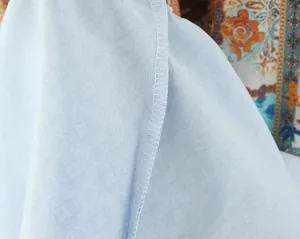 Nahaufnahme einer hochwertigen weißen Overlock-Naht an einem hellblauen Rockstoffdetail