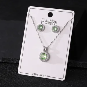 Detail of elegant silver jewelry set featuring green round zircon necklace and earrings