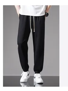 Close-up detail view of men's loose black cotton sweatpants with adjustable white drawstring.