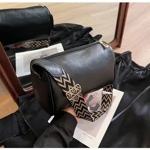 Detailed view of the black pillow bag featuring a wide woven chevron strap.