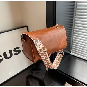 Close-up detail of a brown faux-leather pillow bag featuring a geometric wide strap