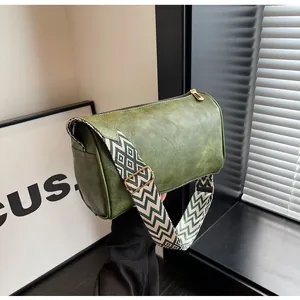 Close-up of stylish green pillow bag featuring a wide ethnic patterned crossbody strap