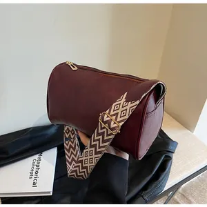 Detail of a burgundy faux leather pillow bag with a stylish patterned wide strap.