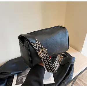 Detailed side view of a black pillow bag featuring a wide geometric pattern fabric strap.