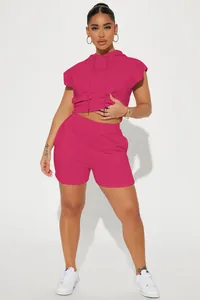 Full body view of a woman in a vibrant pink sleeveless hoodie and matching shorts set.