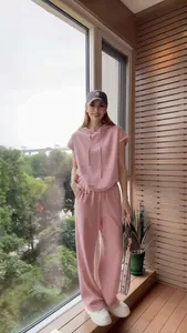 Donna che indossa un completo sportivo casual rosa con cappuccio in un ambiente interno