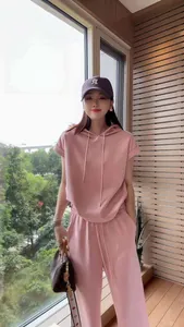 Casual women's pink short-sleeved hooded tracksuit set shown on a model by a window