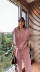 Tuta sportiva casual rosa da donna con cappuccio mostrata da una modella vicino alla finestra