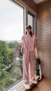 Woman wearing a pink two-piece casual tracksuit with hooded top and wide-leg pants.