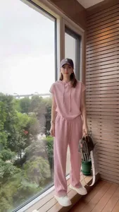 Donna che indossa una tuta casual rosa a due pezzi con cappuccio e pantaloni larghi.