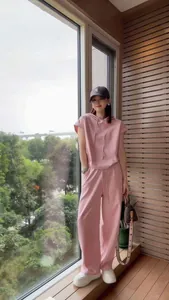 Full body shot of a woman in a pink two-piece casual suit on a balcony.