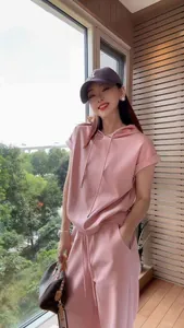 Asian model wearing a pink short-sleeved hoodie and casual jogger pants set outdoors.