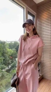 Modella asiatica con felpa rosa a maniche corte e pantaloni sportivi coordinati.