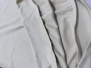 Close-up macro detail of high-quality overlock stitching on beige casual knit fabric