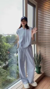 Full body view of a woman wearing a light blue short-sleeved hooded tracksuit set