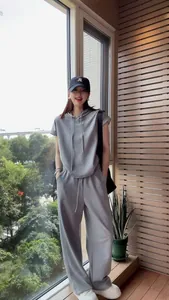 Full-body shot of a women's grey two-piece casual hooded sportswear set in a balcony setting.