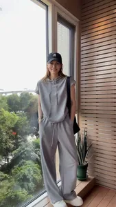 Inquadratura intera di un set sportivo grigio due pezzi con cappuccio da donna su un balcone.