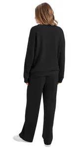 Back view of a woman wearing a black long-sleeve sweatshirt and matching wide-leg trousers