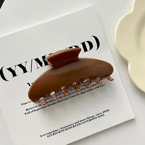Detailed macro view of a large brown acrylic shell-shaped hair claw clip for elegant styling.