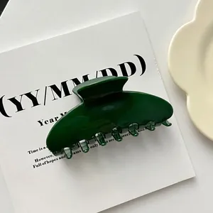 Close-up of a large dark green shell-shaped acrylic hair claw clip on a white background.